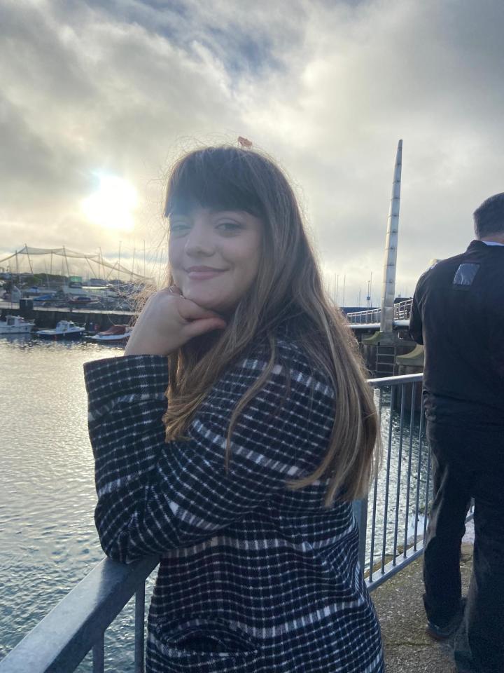 Woman in a black and white coat by the water.