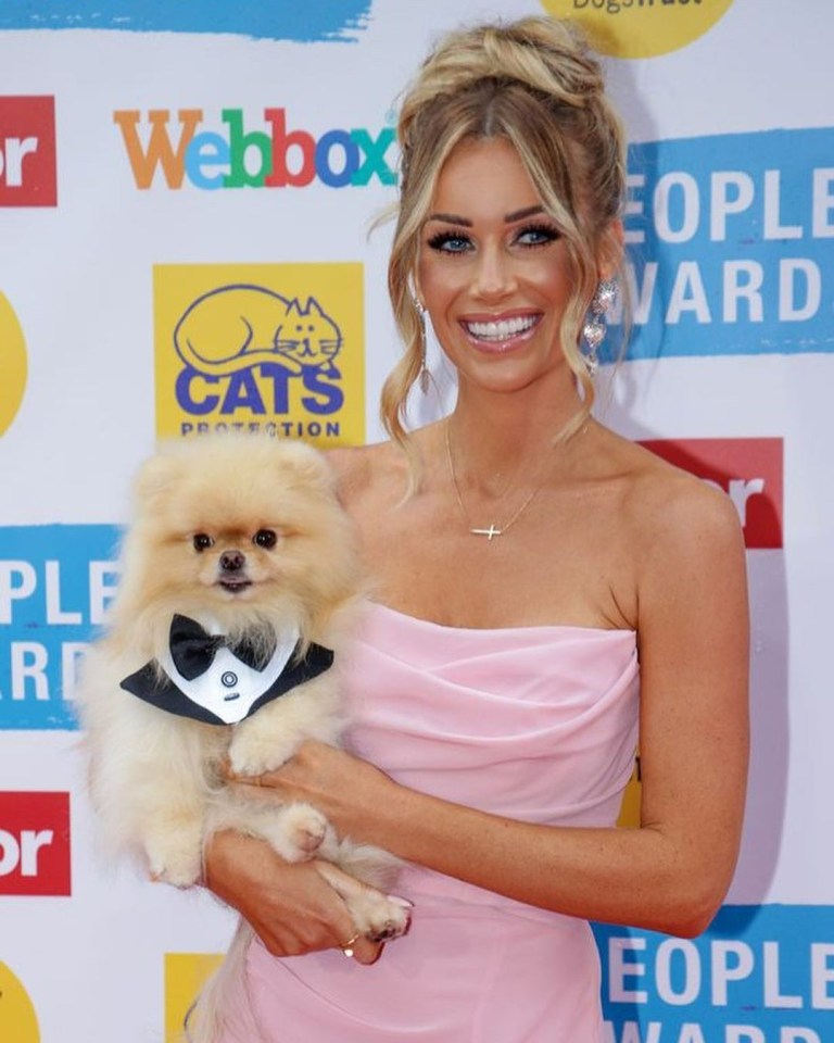 Laura Anderson holding her Pomeranian dog in a tuxedo bow tie.