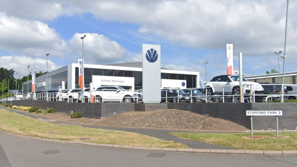 Photo of a large Volkswagen dealership with many cars on the lot.