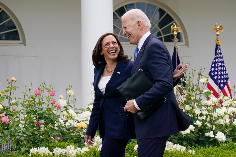 President Biden and Vice President Harris laughing while walking in the White House Rose Garden.