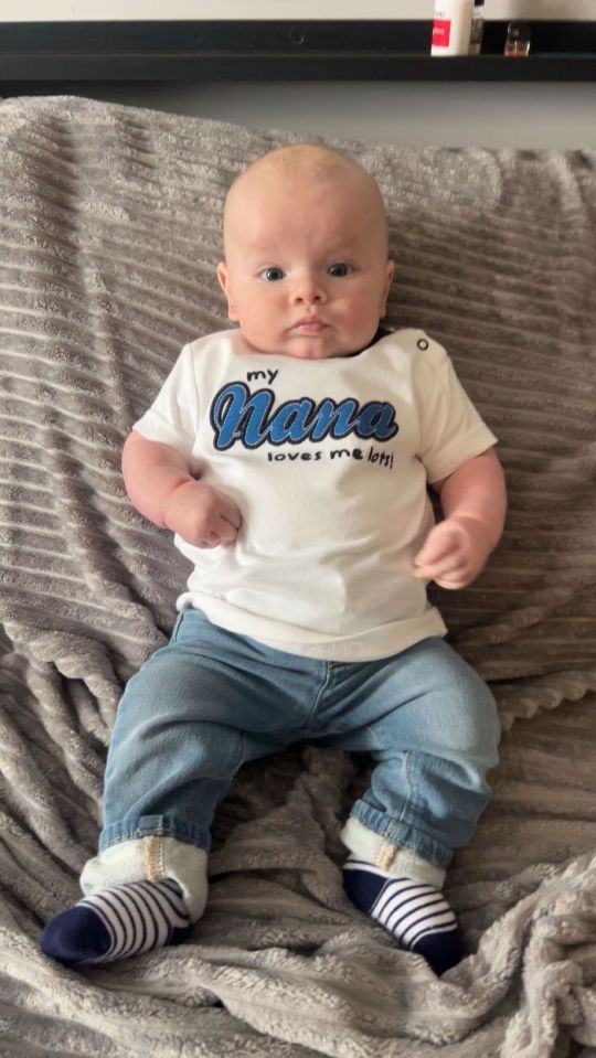 Baby boy wearing jeans and a shirt that says "My Nana loves me lots!"