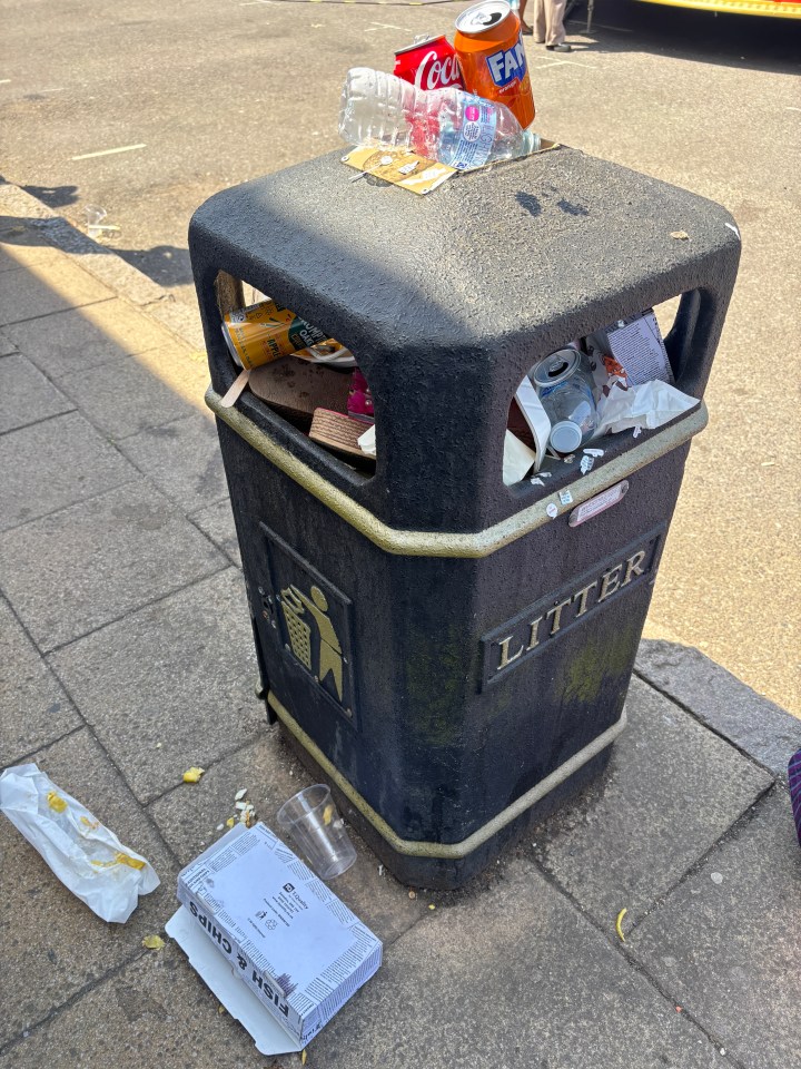 Overfilled litter bin with discarded food and drink containers.