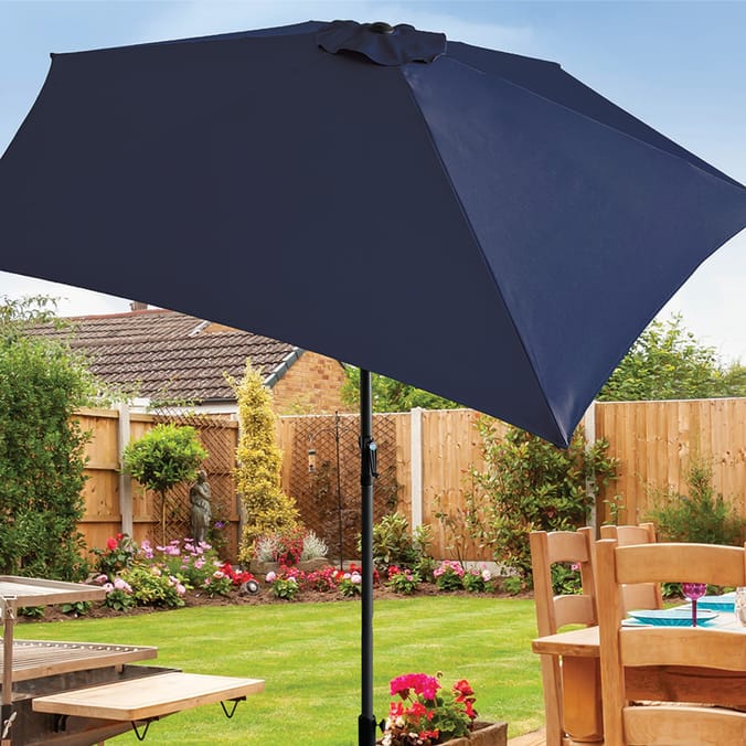 Navy blue crank and tilt parasol in a garden.