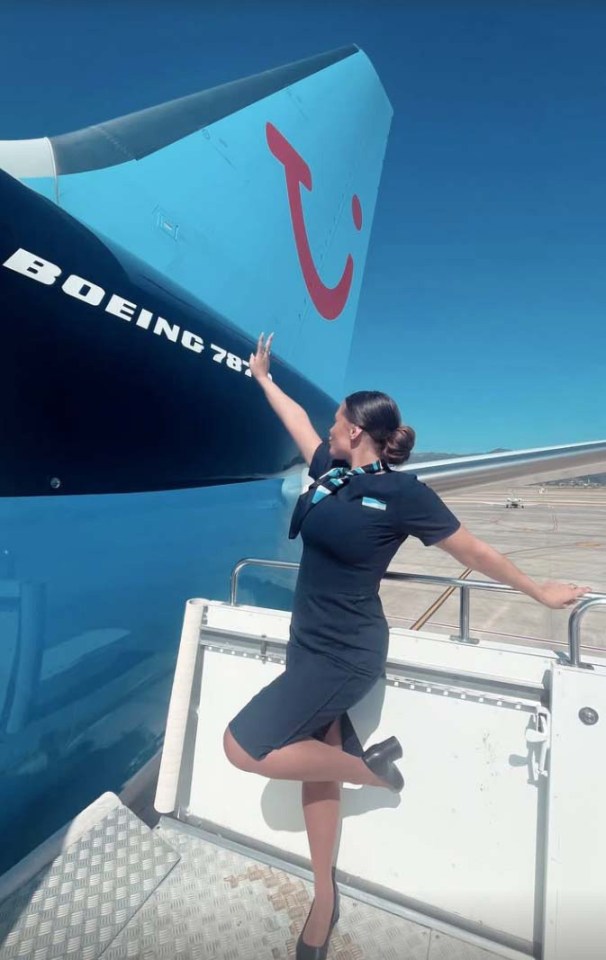 Flight attendant posing by an airplane tail.