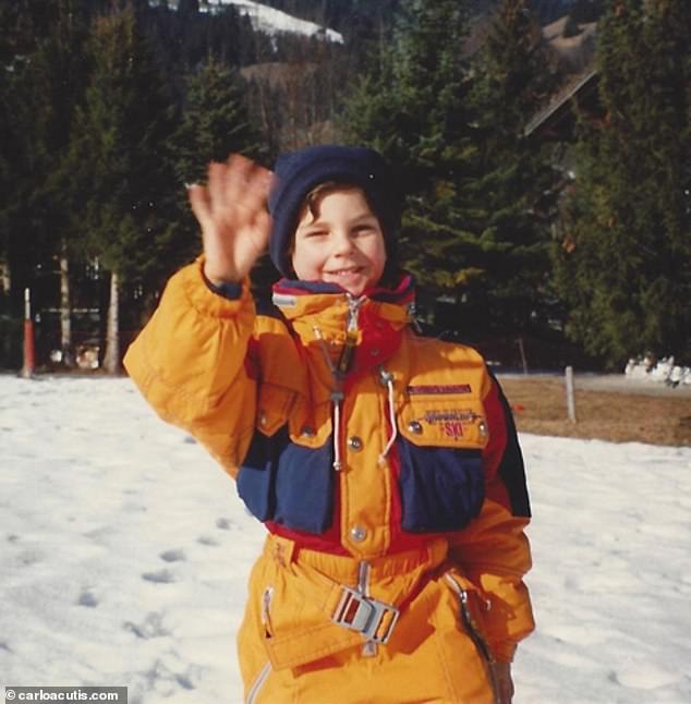 Acutis is pictured as a young boy waving to the camera as he enjoys a holiday in the snow