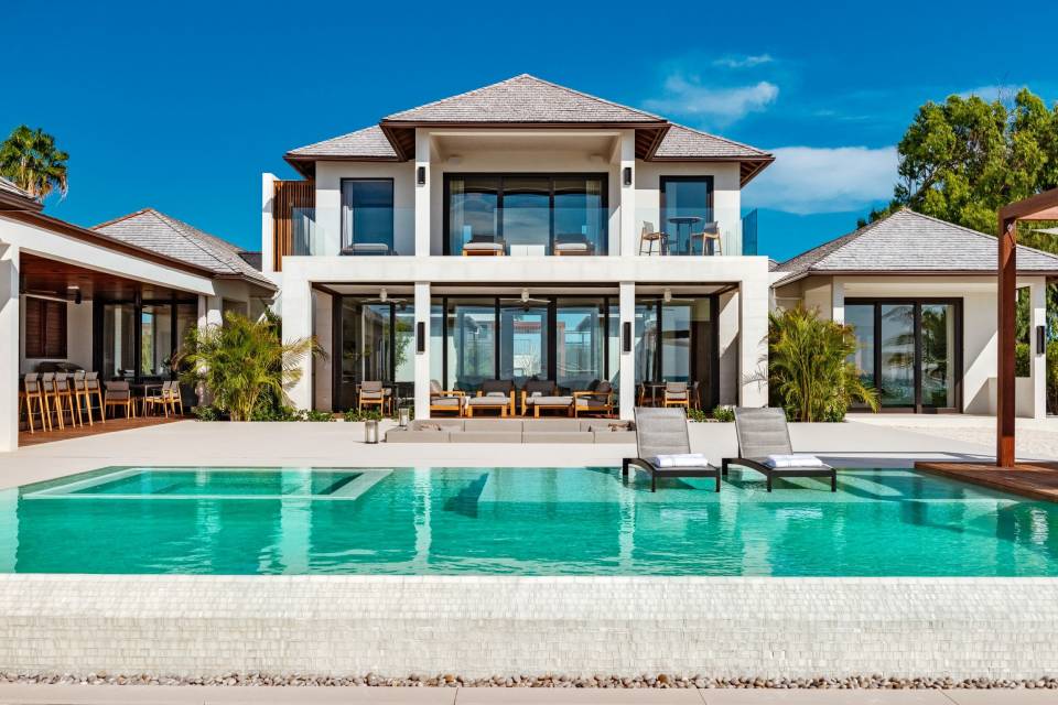 Turks & Caicos beach mansion with pool and lounge chairs.