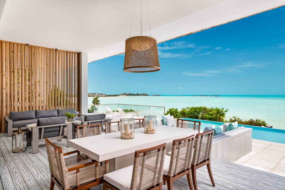 Oceanfront patio with dining table and seating area.