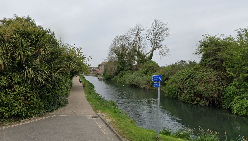 Canal path with lush greenery.