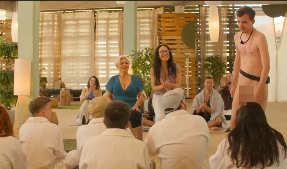 A group of people in bathrobes watching a man and two women in a workshop.