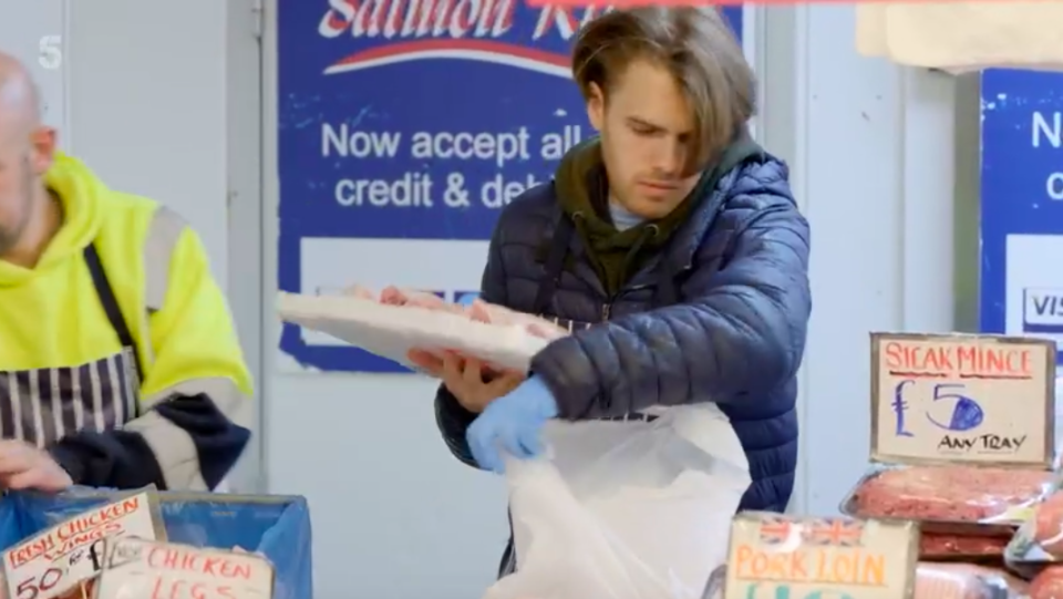 A man bagging meat at a butcher shop counter.