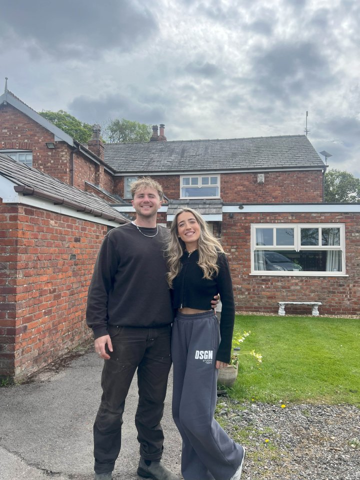 Couple standing in front of their brick house.