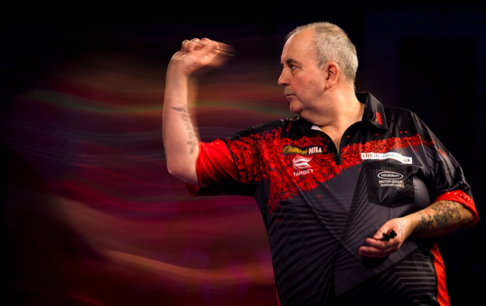 Phil Taylor throwing a dart during a darts match.