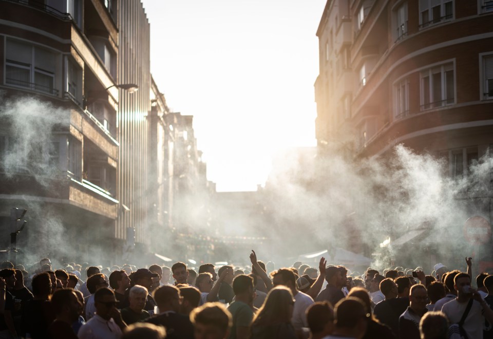Crowd of people in a city street, smoke in the air.