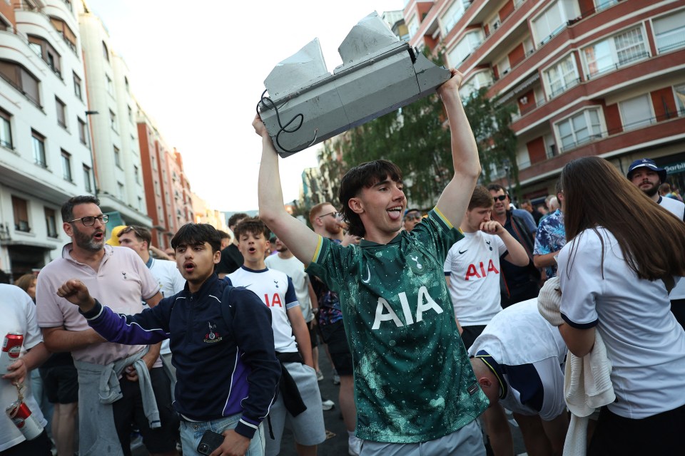 A man holds up a broken traffic light while celebrating with other soccer fans.