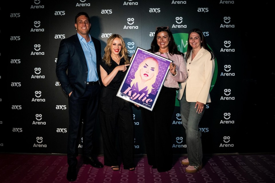 Kylie Minogue holding a commemorative plaque for being the most performed female artist at an arena.