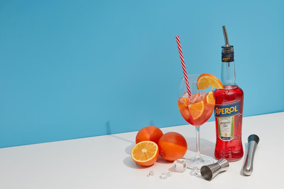 Aperol Spritz cocktail with oranges and bottle.