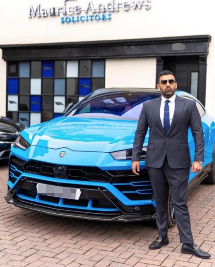 Man in suit standing in front of blue Lamborghini Urus.