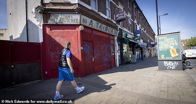 A boarded up butchers with graffiti across its exterior is on the heart of the high street