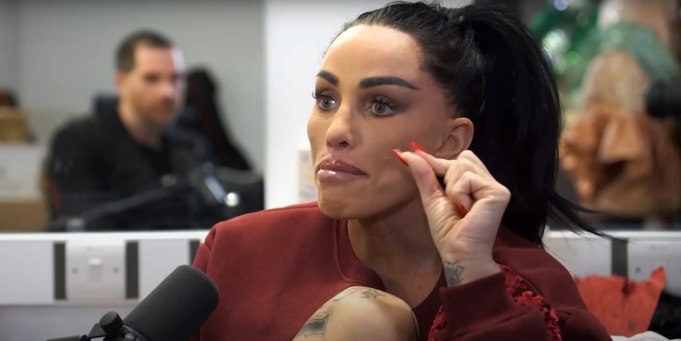 Katie Price in an interview, touching her face.