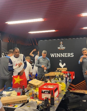 Tottenham Hotspur players celebrating in a messy dressing room after a win.