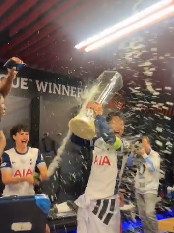 Tottenham Hotspur players celebrating with champagne in the locker room.