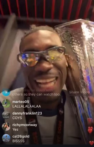A man in sunglasses holding a trophy in a dressing room.