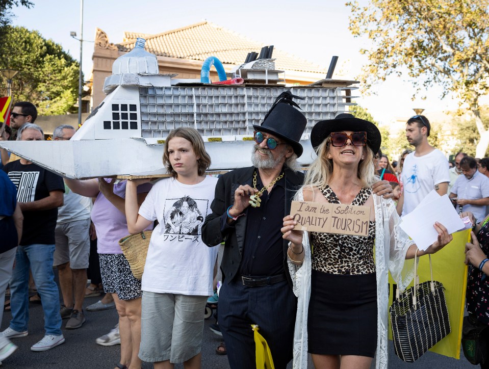 Protestors carry a cardboard cruise ship model and a sign advocating for quality tourism.