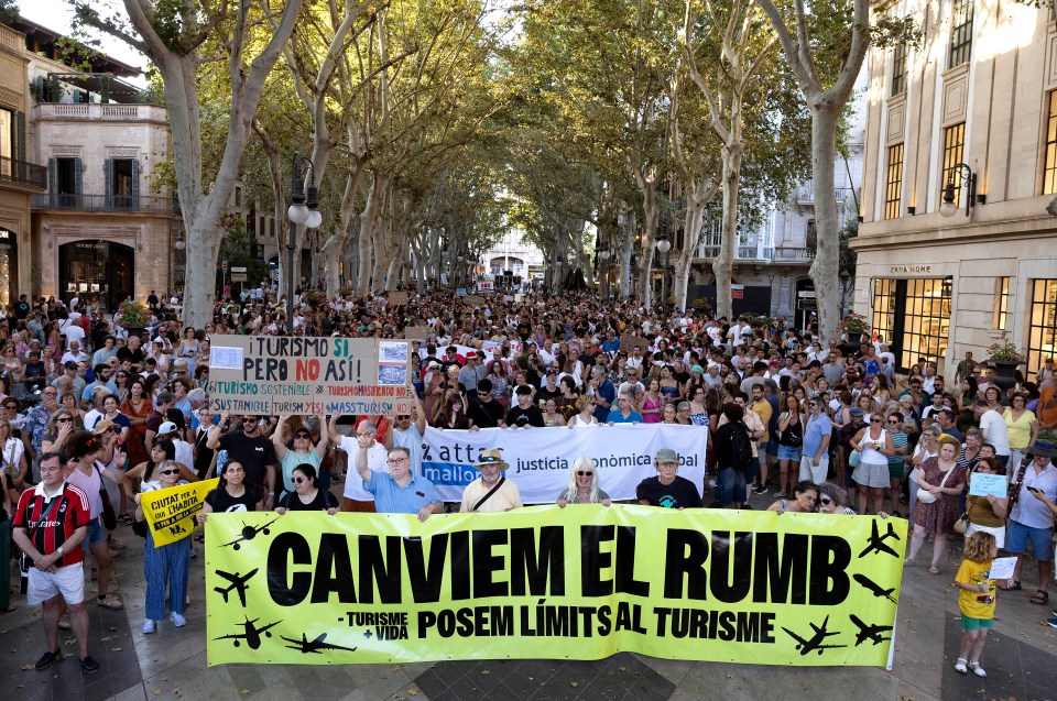 Protestors in Palma de Mallorca holding a banner that reads "Canviem el Rumb - Turisme + Vida" advocating for limits on tourism.