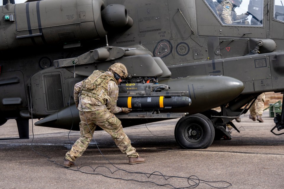 A soldier loading a Hellfire missile onto an Apache helicopter.