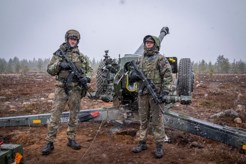 Two Finnish conscripts standing by an artillery piece during a NATO exercise.
