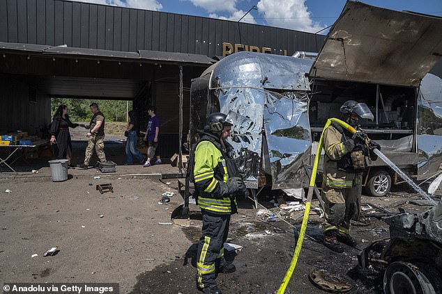 Firefighters extinguish a van fire following a Lancet drone strike at a roadside cafe in Raihorodka, Lyman District, Ukraine