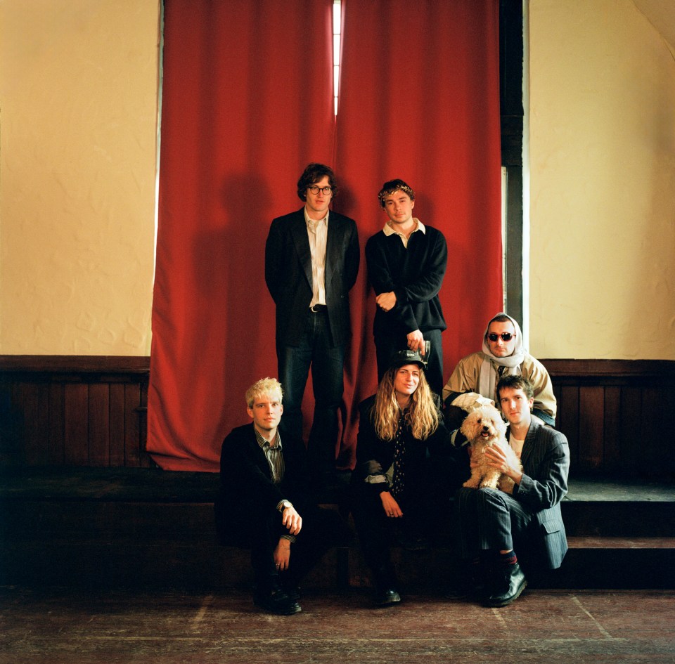 Band posing for a photo with a small dog.
