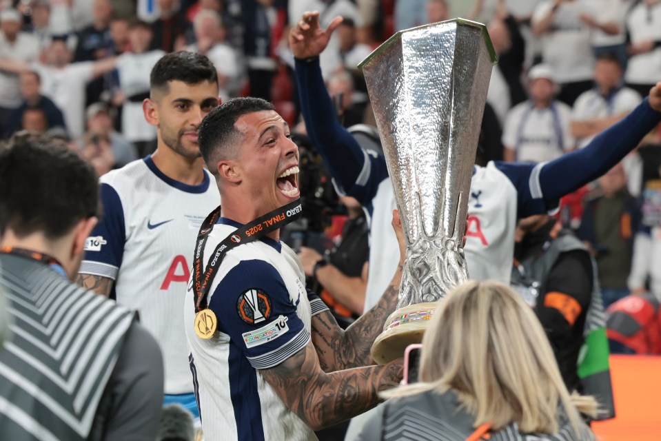 A Tottenham Hotspur player celebrates a victory, holding the UEFA Europa League trophy.