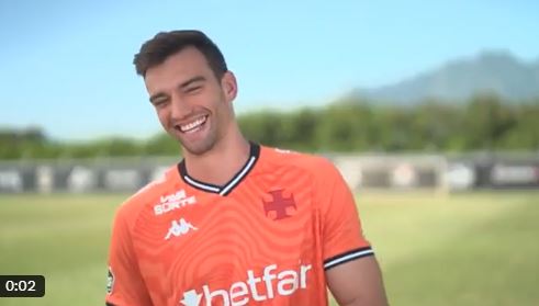 Smiling soccer player in orange jersey.