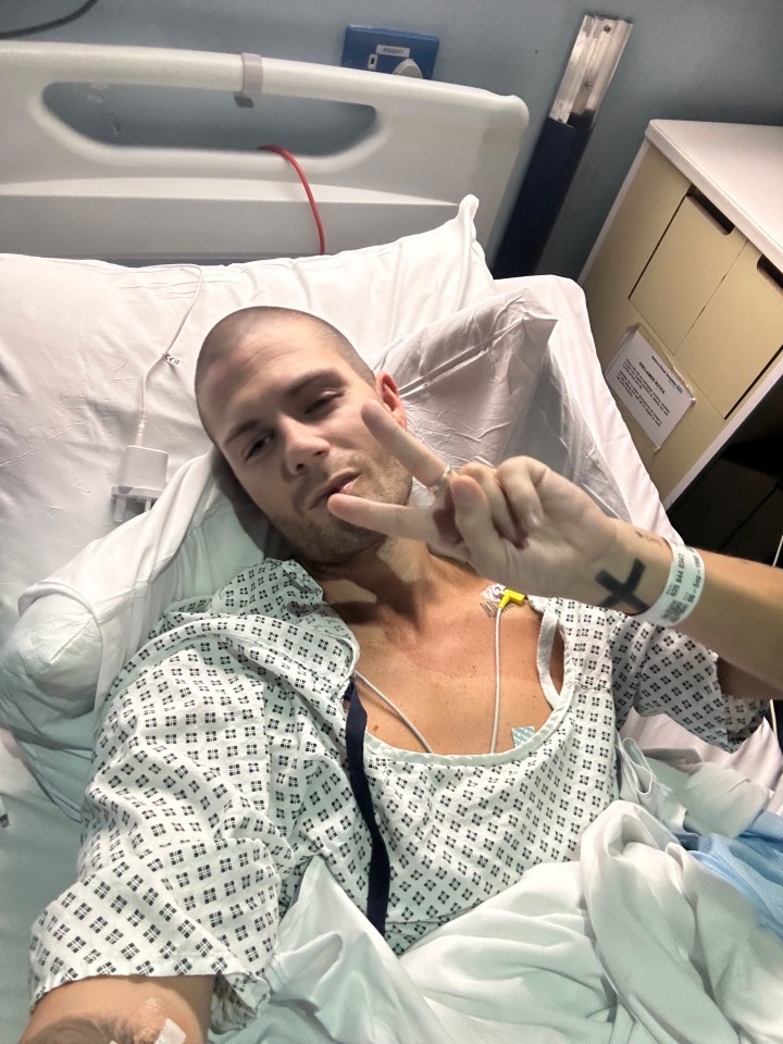 Man in hospital bed giving peace sign.