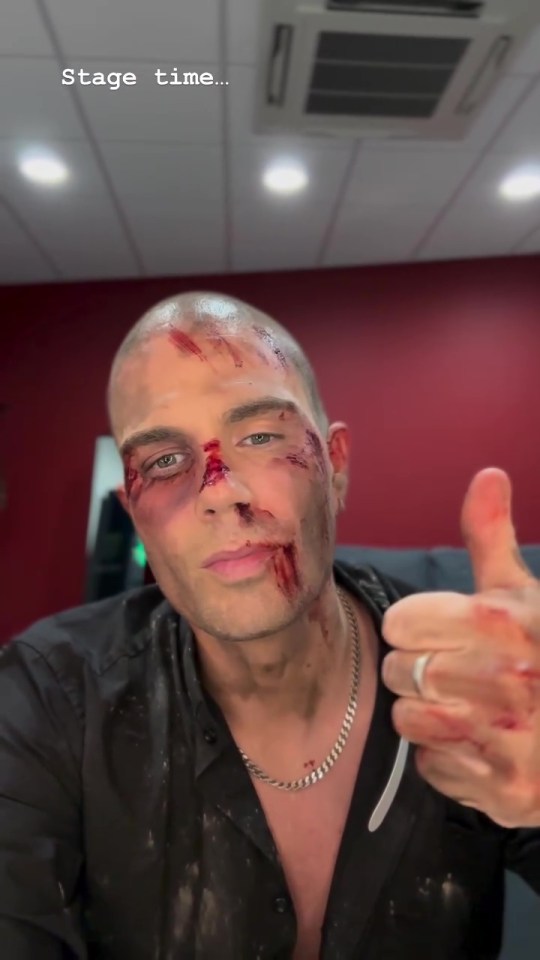 Max George with stage makeup giving a thumbs up.