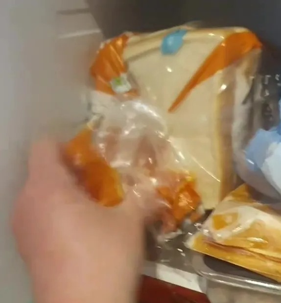Hand reaching into a refrigerator filled with various food items.