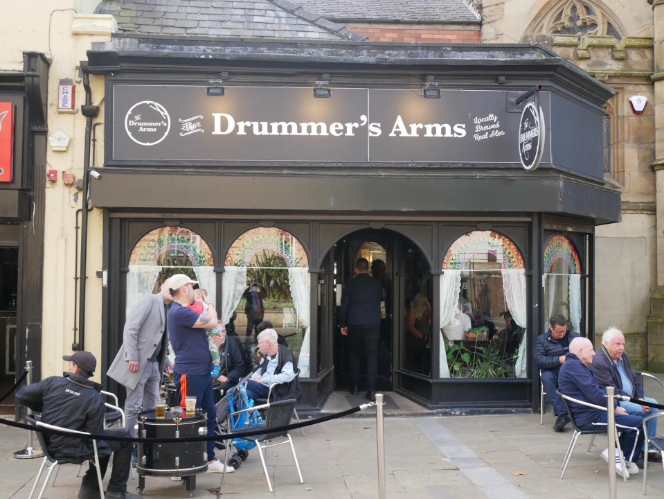 Exterior view of the Drummer's Arms pub with patrons sitting outside.