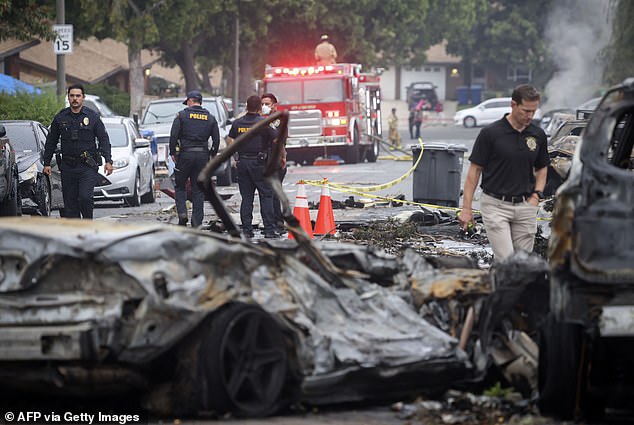 The crash left a "gigantic debris field" and damaged some 15 homes and parked cars. Investigators are seen combing through the crash site on Thursday