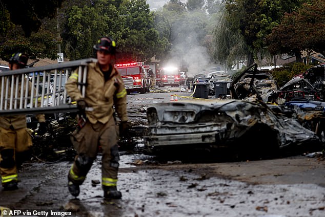 Firefighters work the site where a small plane crashed into a San Diego, California, residential street on May 22, 2025
