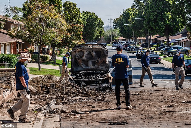 Members of the the Federal Bureau of Investigation (FBI) walk around the crash site after a small plane crashed into a neighborhood, setting homes and vehicles on fire