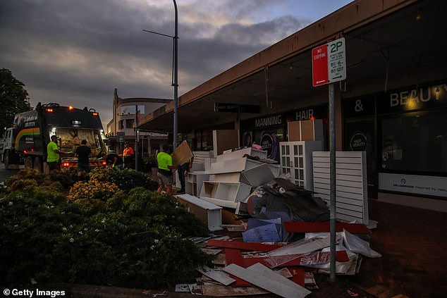Workers load piles of debris onto a garbage truck following a flood at Pulteney Street