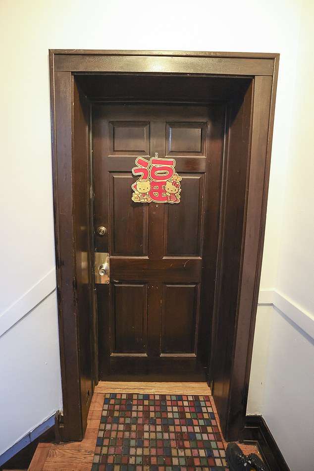On the dark wood front door is a cardboard graphic of a Hello Kitty Chinese New Year decal, with featuring Kitty and her friend Dear Daniel with the Chinese word for 'Blessing'