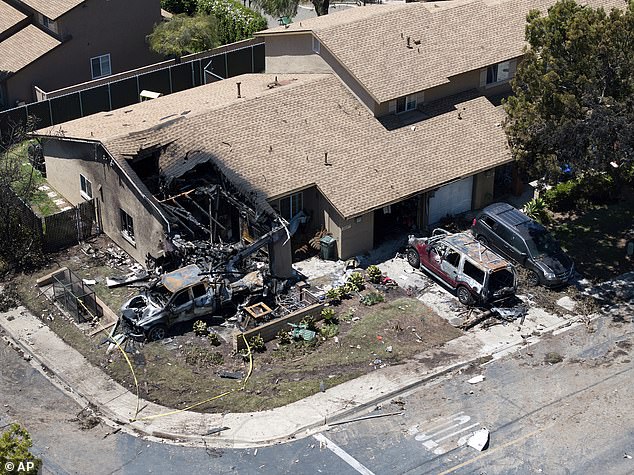 Debris covers the ground after a small plane crashed into a San Diego neighborhood, setting homes and cars on fire and forcing evacuations