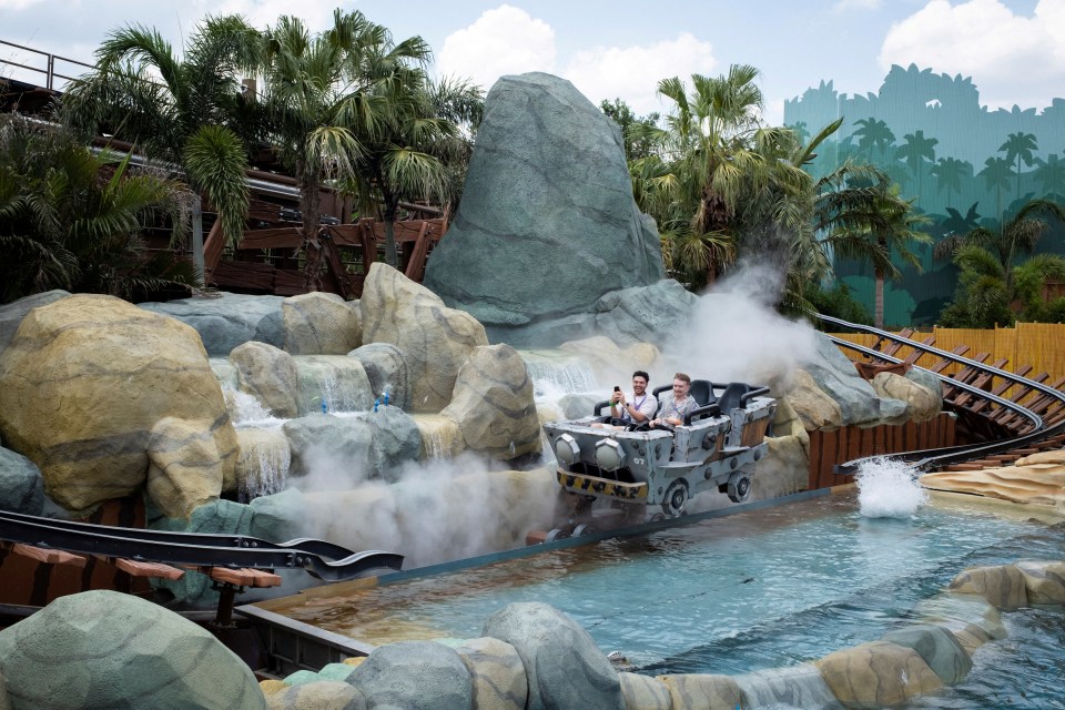 Two people riding Donkey Kong's Mine-Cart Madness roller coaster.