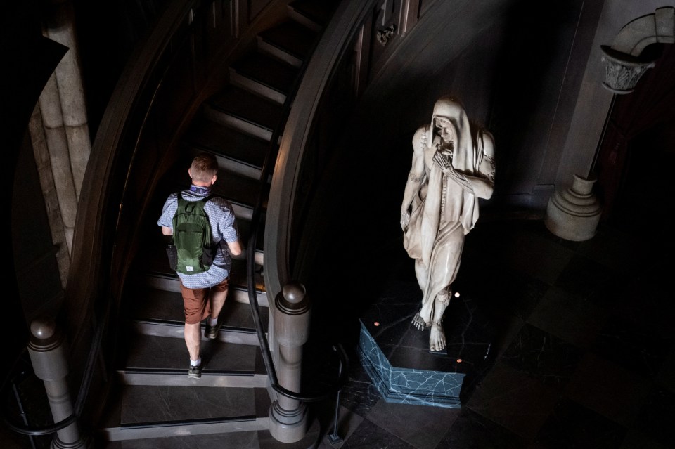 Person walking up a staircase past a statue.