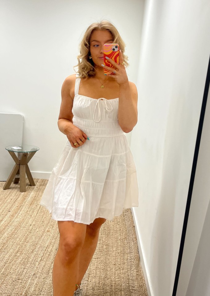 Woman in white dress taking a selfie.