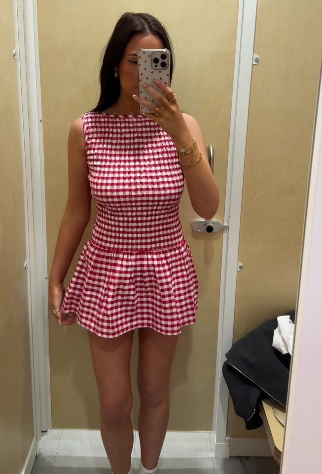 Woman in a red and white gingham dress in a changing room.