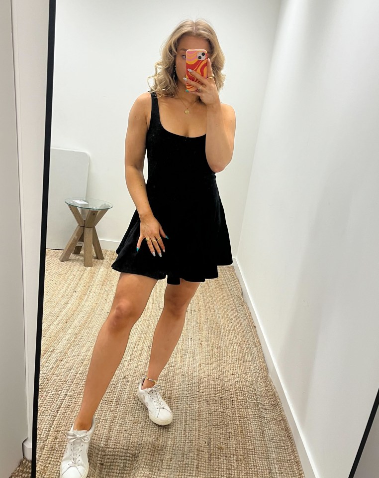 Woman in black dress taking a selfie.