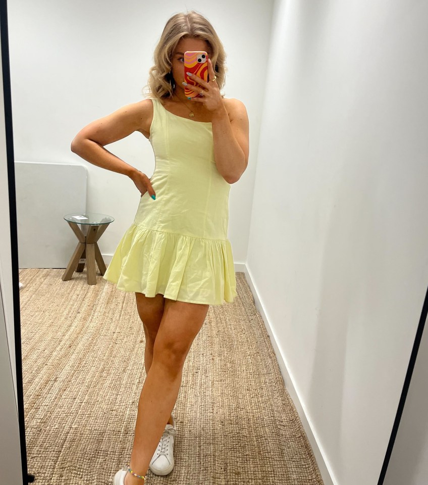 Woman in a pale yellow sundress taking a selfie.